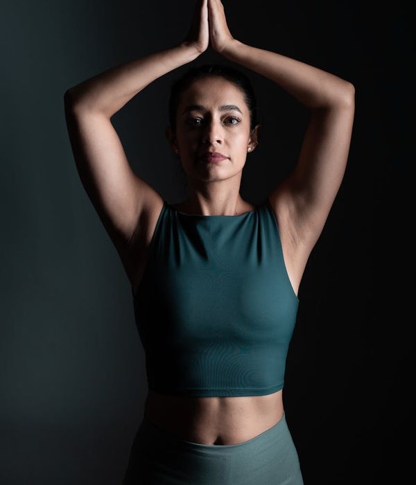 Woman in a calm yoga pose in a dark studio with mint green light accents.